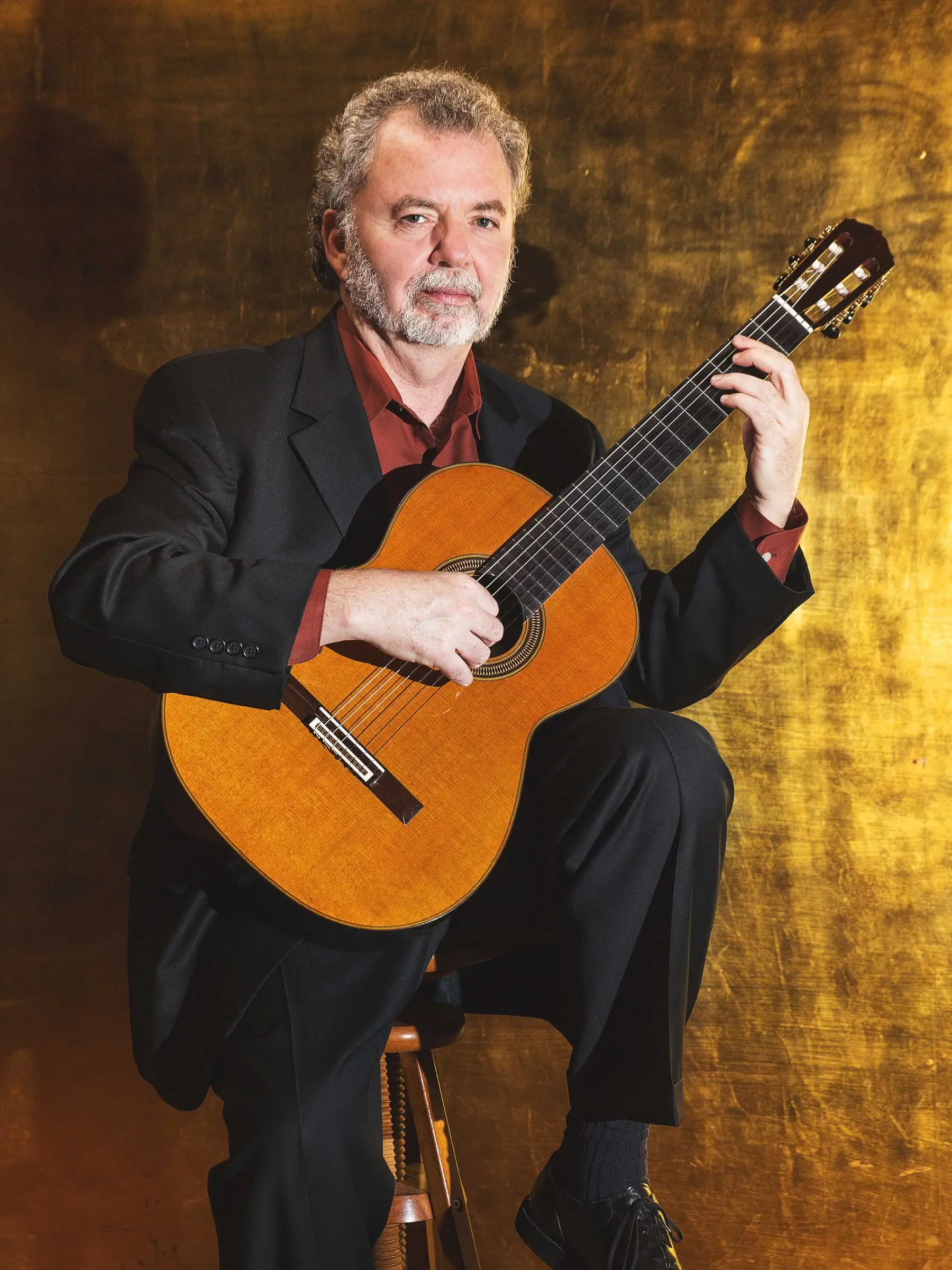 Manuel Barrueco with his guitar before a gold-leaf backdrop